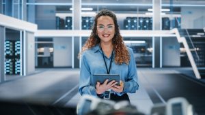 A professional woman in a modern tech environment holding a tablet, representing a streamlined B2B partner experience and frictionless onboarding.